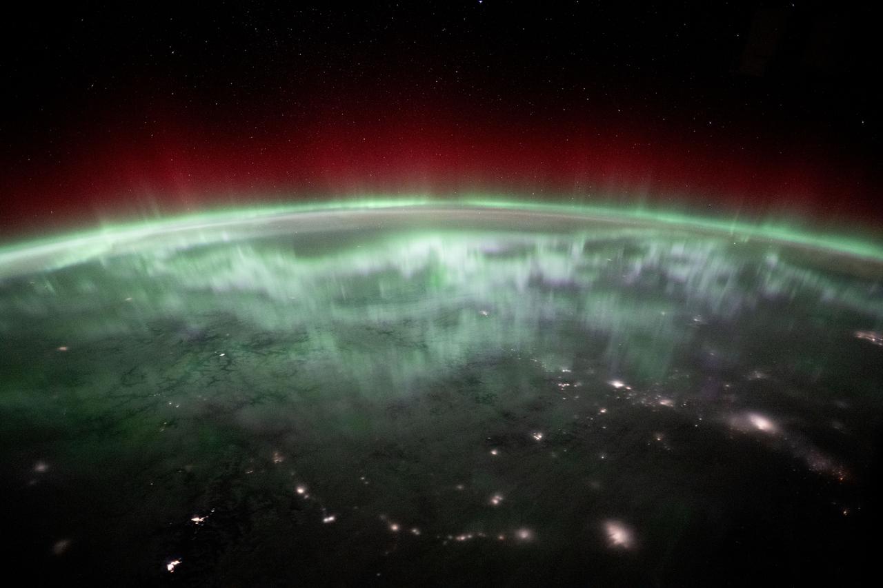 Green and red aurora above city lights in Canada.
